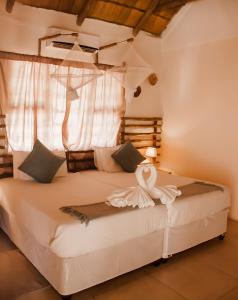 a bedroom with a large white bed with a window at Leeville Guesthouse in Kasane