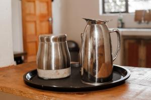 eine Kaffeekanne und einen Krug auf einem Teller auf einem Tisch in der Unterkunft Leeville Guesthouse in Kasane