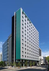 a tall white building with a green stripe on it at Prince Smart Inn Hakata in Fukuoka