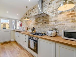 a kitchen with white cabinets and a brick wall at Hidden Winds Cottage in Guisborough