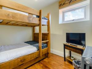 a bedroom with bunk beds and a flat screen tv at Hidden Winds Cottage in Guisborough