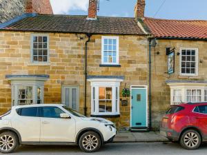two cars parked in front of a brick house at Hidden Winds Cottage in Guisborough