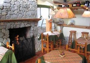 a living room with a stone fireplace and a table at Hostería Traunco in Villa La Angostura