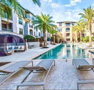 een zwembad met 2 ligstoelen en palmbomen bij The Turquoise Suite in Houston