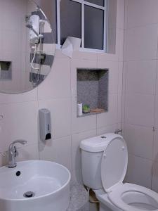 uma casa de banho com um WC, um lavatório e um espelho. em Home Feel-Hibiscus Suites em Kampar
