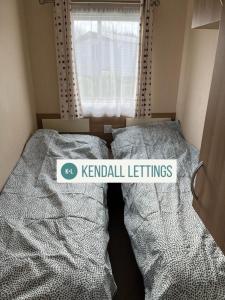 a bedroom with two beds with a kendall lettuce sign on them at Tebay (Green Lawns) in Selsey