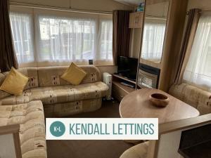 a living room with a couch and a table at Tebay (Green Lawns) in Selsey