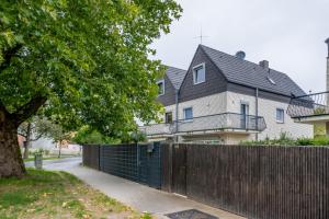 a fence in front of a house with a tree at up to 3 private rooms with 2 bathrooms in Hannover