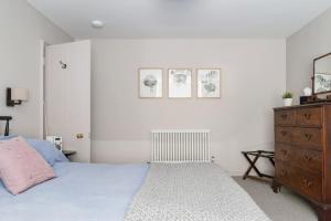 a white bedroom with a bed and a dresser at Berkeley Square Apartment in Bristol