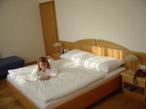 a woman laying on a large bed at Pension Schlossblick in Nebersdorf