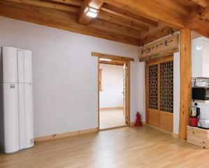 an empty room with a refrigerator and a door to a kitchen at Saranbang Pension in Gapyeong