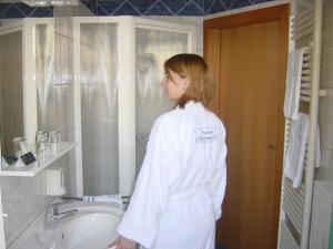 a woman standing in a bathroom next to a sink at Pension Schlossblick in Nebersdorf