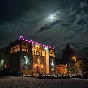 un edificio iluminado por la noche con la luna en el fondo en Auberge restaurant Afoud, en Agoudal