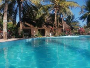 a swimming pool in front of a house with palm trees at Maua beach in Kizimkazi