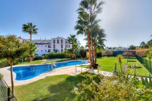 a pool in a yard with palm trees and a building at Maison Arlette in Mijas Costa