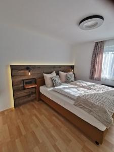 1 dormitorio con 1 cama grande y cabecero de madera en Ferienwohnungen Kienesberger, en Tiefgraben