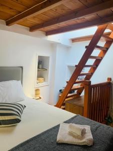 una camera con un letto e una scala in legno di Elia Concept Apartments a Ano Syros