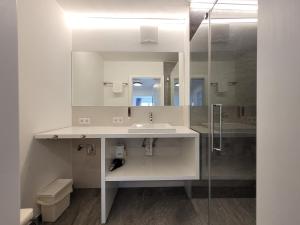 a white bathroom with a sink and a mirror at Panorama Apartments - Steinbock Lodges in Zell am See