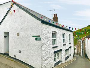 a white building with flags on a street at Zion Cottage in Gorran Haven