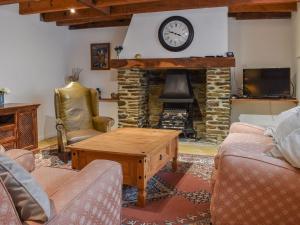 a living room with a fireplace with a clock on the wall at Zion Cottage in Gorran Haven