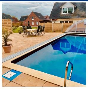 a swimming pool in a backyard with a table and chairs at Haus Weda in Krummhörn