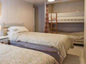 a bedroom with two beds and a bunk bed at Zion Cottage in Gorran Haven