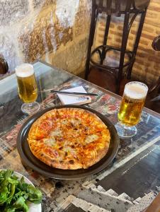 una pizza en una mesa con dos vasos de cerveza en El manzano, en Castrojeriz