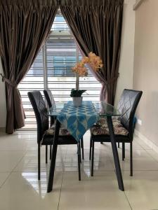uma mesa de vidro com cadeiras e um vaso com flores em Hud hud Homestay Gelang Patah em Nusajaya