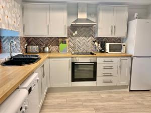 a kitchen with white cabinets and white appliances at Bracknell Cottage in Freystrop