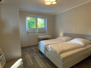 ein Schlafzimmer mit zwei Betten und einem Fenster in der Unterkunft Exclusives Appartement auf Fehmarn in Petersdorf auf Fehmarn
