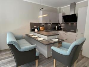 une cuisine avec une table, deux chaises et un comptoir dans l'établissement Exclusives Appartement auf Fehmarn, à Petersdorf auf Fehmarn 32 autres photos