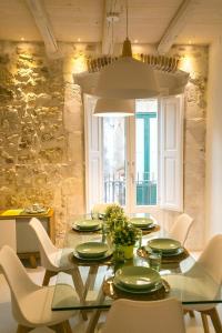 una sala da pranzo con tavolo in vetro e sedie bianche di Veronique by Dimore in Sicily a Siracusa