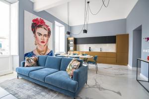 ein Wohnzimmer mit einem blauen Sofa und einem Bild einer Frau in der Unterkunft Frida apartments by Dimore in Sicily in Syrakus