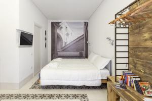 een slaapkamer met een wit bed en een trap bij Dione Apartments by Dimore in Sicily Ortigia in Siracusa
