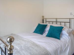 a white bed with two blue pillows on it at No 1 Overman in Bowburn