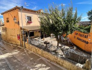 a building on a street with a tree next to it at El manzano in Castrojeriz