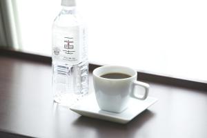 a cup of coffee and a bottle of water on a table at Shizutetsu Hotel Prezio Shizuoka-Ekikita in Shizuoka