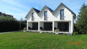 a white house with a lawn in front of it at Malaga in Gąski