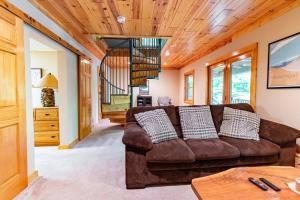 a living room with a brown couch and a staircase at Hygge Up North Cabin in Traverse City