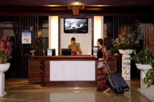 a woman standing at a counter with her luggage at Best Western Resort Kuta in Kuta