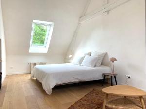 a white bedroom with a bed and a table at La Maison Vivante, chambres d'hotes au coeur du Perche in Les Étilleux
