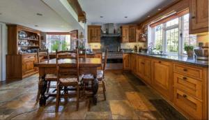 a large kitchen with wooden cabinets and a table and chairs at 6 Bed Mansion With Tennis Court & Swimming Pool in West Horsley