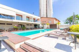 a swimming pool with chairs and a building at JB03 Flat Cocoon a 250m da Praia de Jaguaribe in Salvador