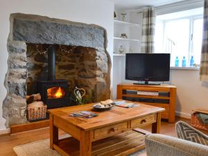 a living room with a stone fireplace and a television at Bryn Hyfryd in Llanrwst