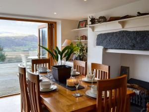 a dining room with a table with chairs and a fireplace at Bryn Hyfryd in Llanrwst