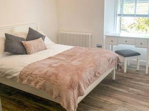 a bedroom with a bed with a desk and a window at Holmbyre Smithy in Dalry