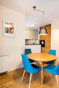 a kitchen and dining room with a wooden table and blue chairs at Sokratesa Estate Ideal Apartment in Warsaw