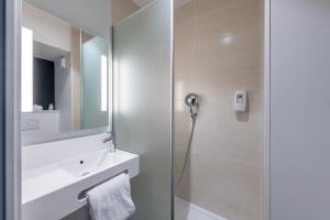 bagno con doccia, lavandino e specchio di B&B HOTEL Dreux Nord a Dreux