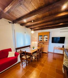 sala de estar con mesa y sofá rojo en House Suestellas, en Teulada