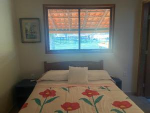 a bedroom with a bed with a flowered blanket and a window at Fazenda a 15 min do centro com Rio Particular in Bonito